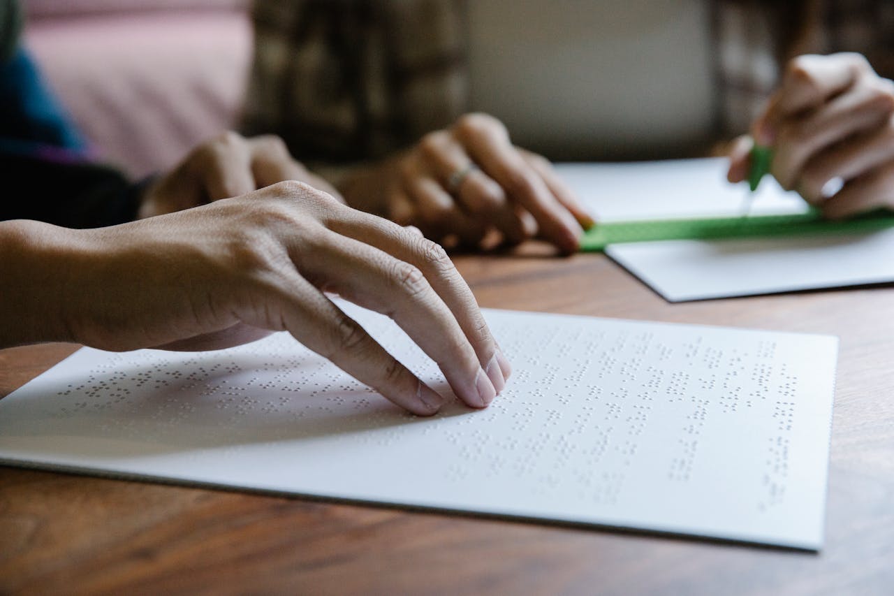 About Hands feel Braille text on paper, demonstrating tactile reading and sensory education.